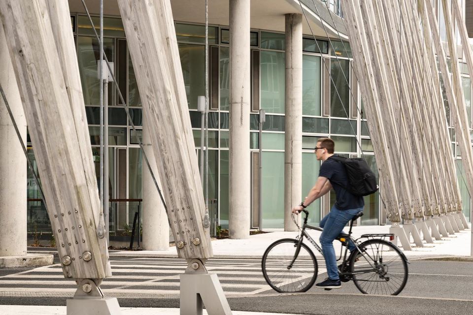 A cyclist passing the timber colonnade at Elmpark Green
